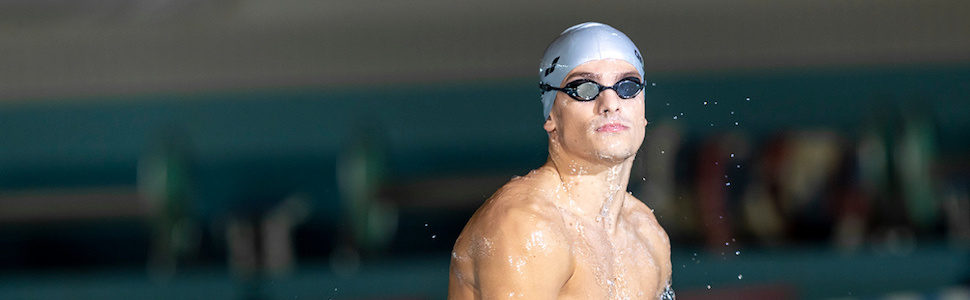 athlete wearing unisex adult silver silicone arena swim cap for swimming and training at indoor pool