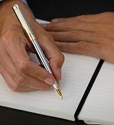 Silver and gold scriveiner rollerball writing on a blank notebook