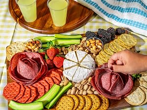 A knife about to get a scoop of cheese from a charcuterie board.