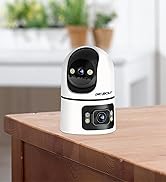 White and black compact desktop robot with round head, circular camera lens, articulated arm, and digital display interface positioned on wooden surface.