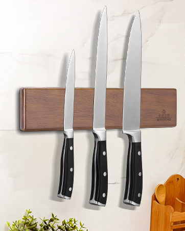 Magnetic wooden knife holder mounted on wall displaying three professional-style kitchen knives with black handles. Wood block features natural grain finish.
