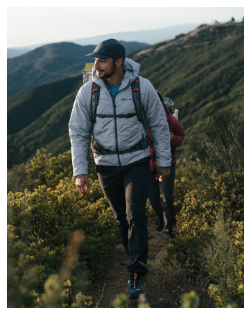 Man walking on grassy hillside wearing Marmot insulated jacket and hiking pants