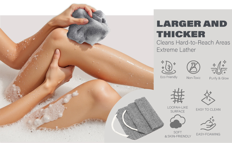 Hands lathering legs with a grey textured bath scrub towel, surrounded by bubbles