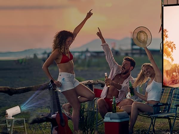 Outdoor movie screening setup at sunset, with people enjoying film projected onto large screen in warm golden lighting.