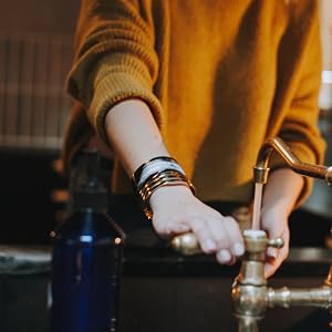 Woman turn on sink faucet.