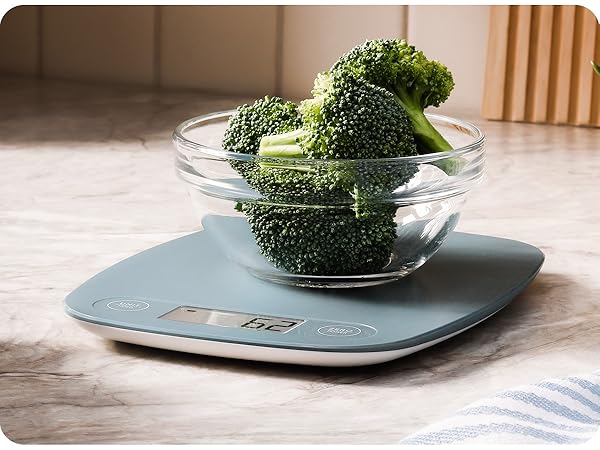 greater goods stone blue kitchen scale on marble countertop weighing bowl of broccoli