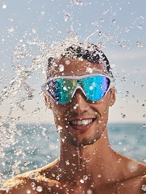 man smiling wearing arena The One swim mask goggle for adults at the beach on a sunny day