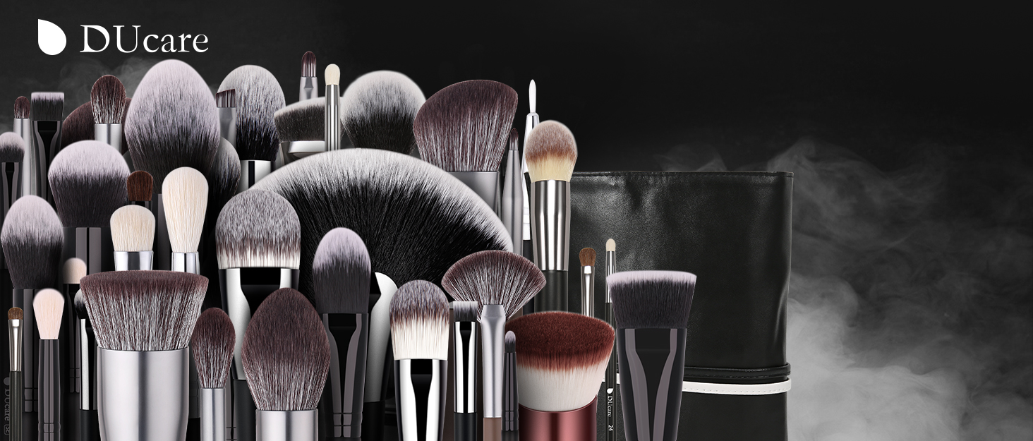Large collection of professional makeup brushes arranged together, featuring various sizes and shapes with silver handles and black to gray bristles.