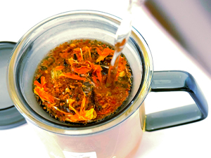 Pouring freshly brewed tea from glass infuser mug showcasing clarity and purity