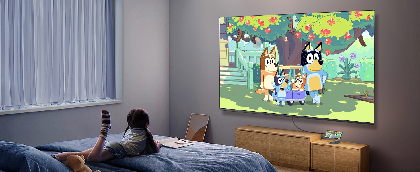 Home theater setup in a bedroom showing animated content projected on wall, with a projector visible and blue curtains on the side.