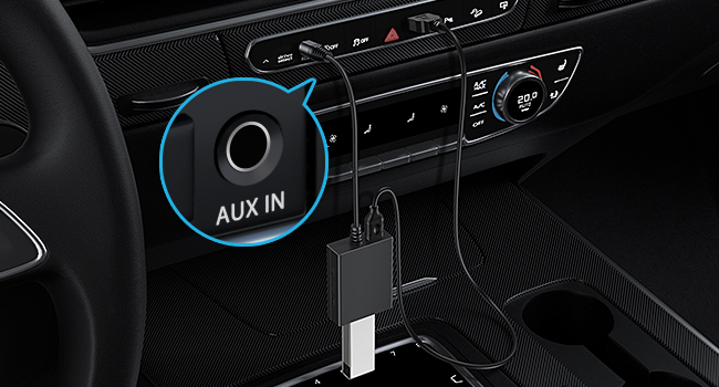 Car interior showing dashboard controls and AUX IN port. Black cable plugged into AUX port, likely for audio connection.