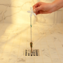Hand pulling the DrainWig out of the drain with a hairball attached