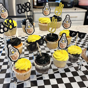 Display of cupcakes or baked goods on a black and white checkered surface with decorative elements.