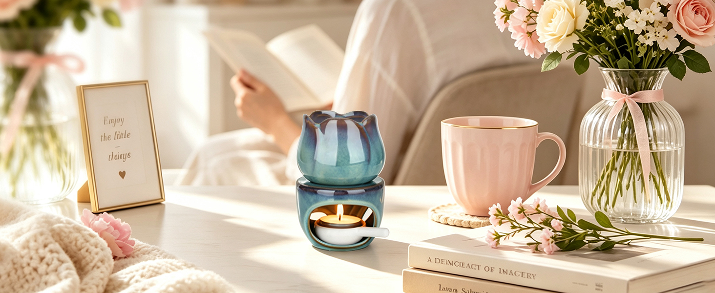 Teal geometric glass vessel with fresh white and pink flowers in clear vases, pink ceramic mug, stacked books, and picture frame on white surface. Minimalist neutral home styling with natural window lighting.