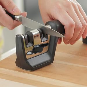 kitchen knife being sharpening in handheld pull through knife and scissor sharpener black and grey
