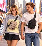 Couple holding hands in Times Square, wearing taupe and black sling bags across their chests.