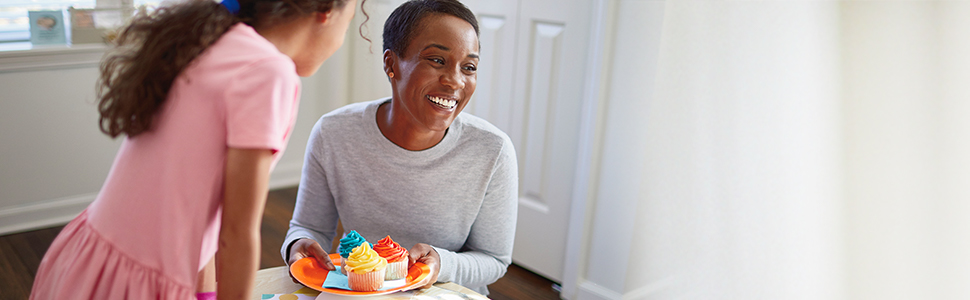 Daughter with mom smiling and holding a plate of colorful cupcakes at a celebration