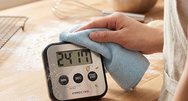 Person wiping digital timer clean with cloth.