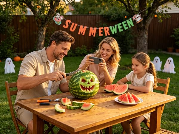 Family carving watermelon face, Summerween banner on fence.