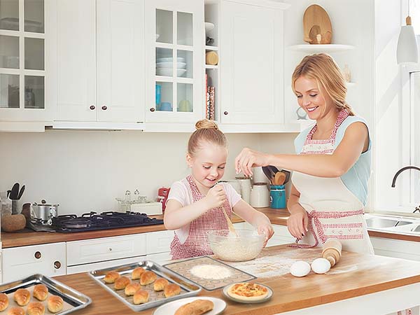 Mother and daughter kneading pastry dough on a nonstick silicone baking mat in a bright kitchen