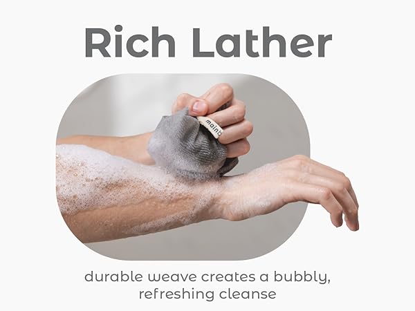 Hands lathering a textured washcloth, creating a foamy cleanse.