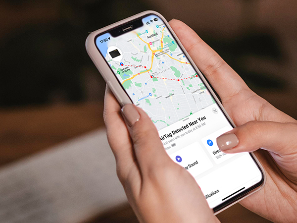 Hands holding smartphone displaying a map application with navigation route. Shows real-world usage of mobile GPS and location services.