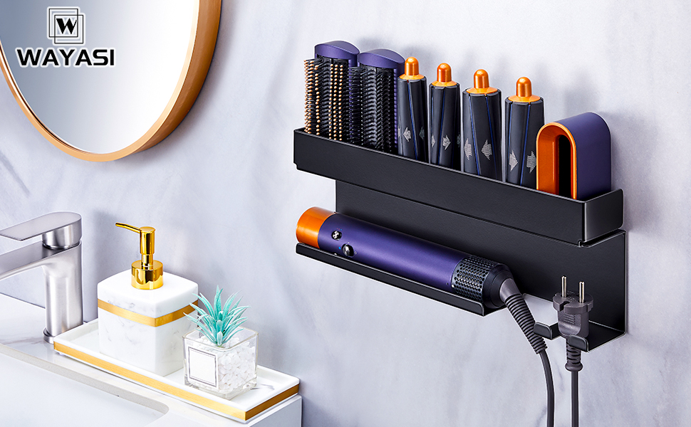 Wall-mounted black hair tool organizer holding multiple styling tools with orange accents, installed above bathroom counter with decorative items.