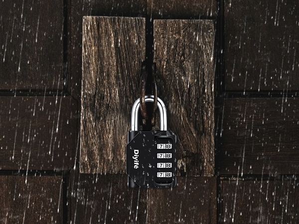 Black combination padlock with four-digit code, hanging on a dark wooden surface. Raindrops visible in the background.