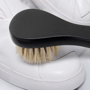 white horsehair shoe polish brush applying white polish to the shoe