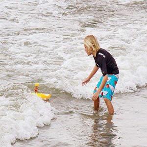 Boy in the surf with his Surfer Dudes toy