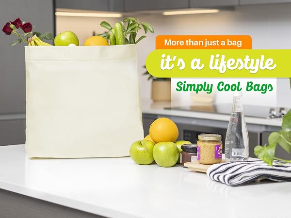 White tote bag on a table with apples lemons water plants and a towel