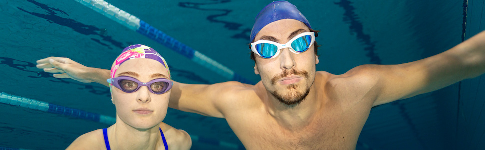woman and man wearing arena The One swim goggles and arena swim caps in an indoor pool