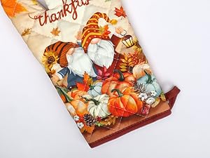 Decorative kitchen towel with Thanksgiving theme featuring pumpkins, fall leaves, and illustrated gnomes in autumn colors.