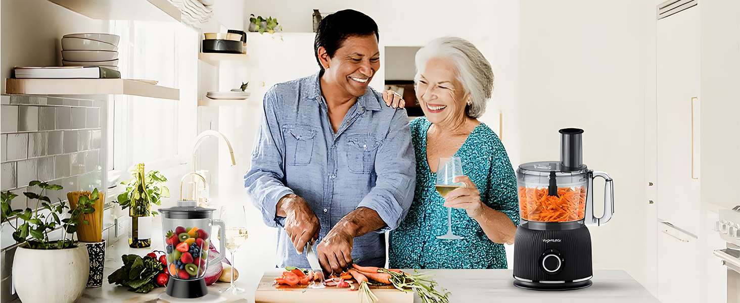 Interior kitchen scene showing two people preparing food together using a food processor or blender on the counter.