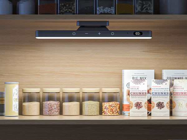 Black LED task light mounted above wooden shelf displaying glass storage jars with dry ingredients and packaged food items.