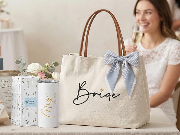 An embroidered Bride tote bag displayed on a table with flowers and bridal shower gift boxes