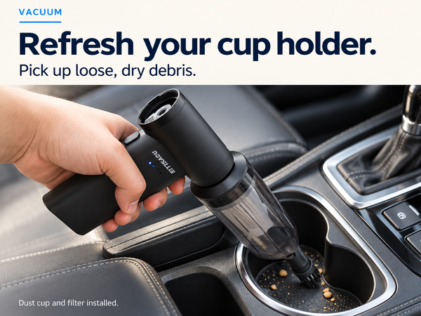 Mini car vacuum with brush nozzle picking up loose dry crumbs from a cup holder