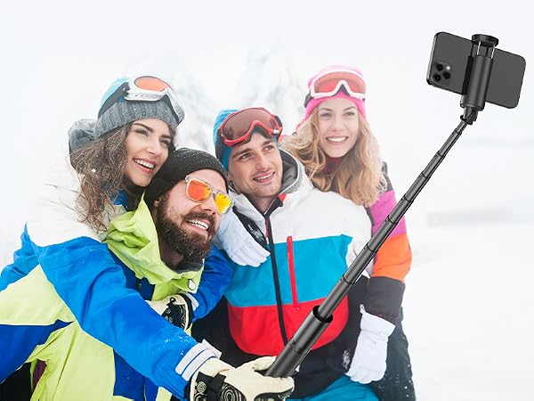 Extended selfie stick being used in snowy conditions, demonstrating outdoor photography capabilities in winter sport setting.