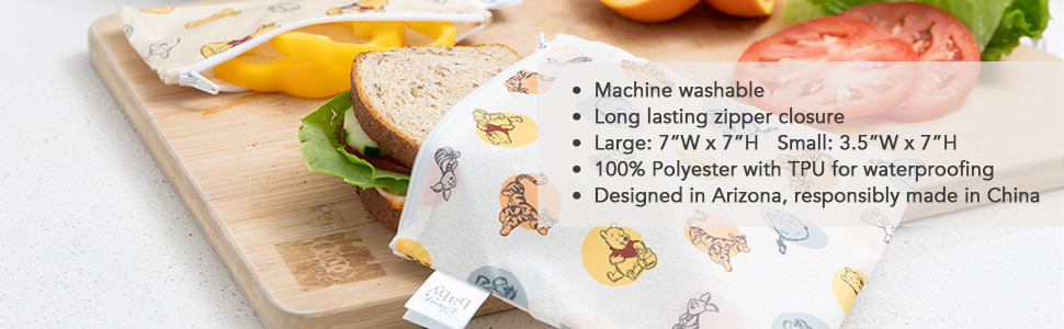 Winnie the Pooh themed cloth snack bag with a sandwich on a wood cutting board