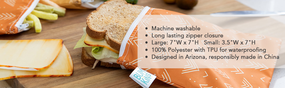 A sandwich inside an orange color cloth snack bag on top of a wood cutting board