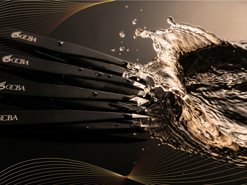 Multiple black brushes with water splash effect, bristles visible, dynamic action shot showing wet texture and movement.