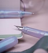 Close-up macro shots of a fountain pen nib on paper, showing different angles and writing positions against a soft pink background.