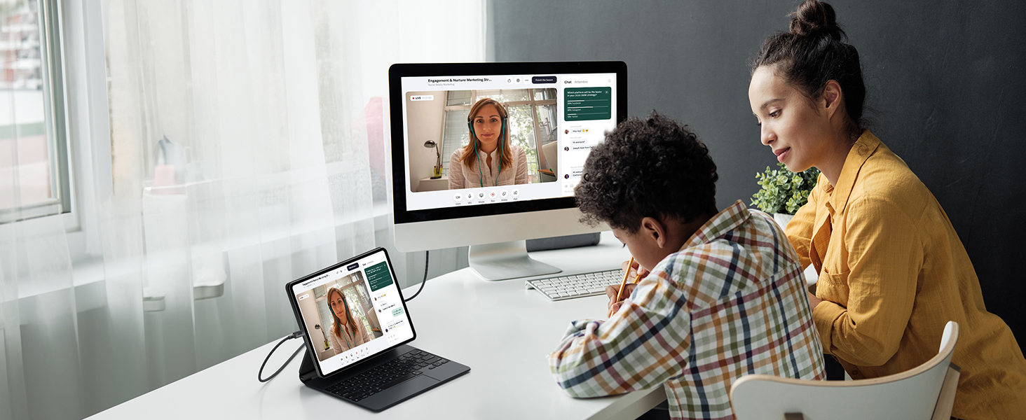 Remote learning or video conferencing setup showing laptop and desktop computer screens displaying virtual meeting interface.