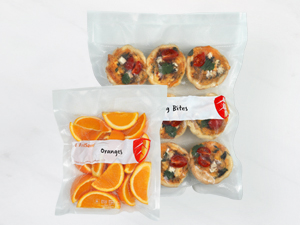 Vacuum-sealed bags containing orange slices and savory bites