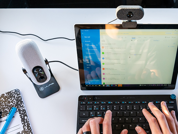 go talk mic next to hand typing on keyboard on a white desk