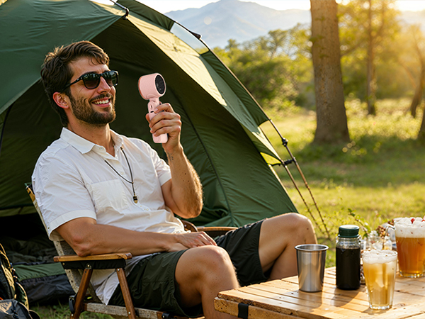 Man camping with pink rechargeable fan outdoors powerful small fan for hot summer days tent