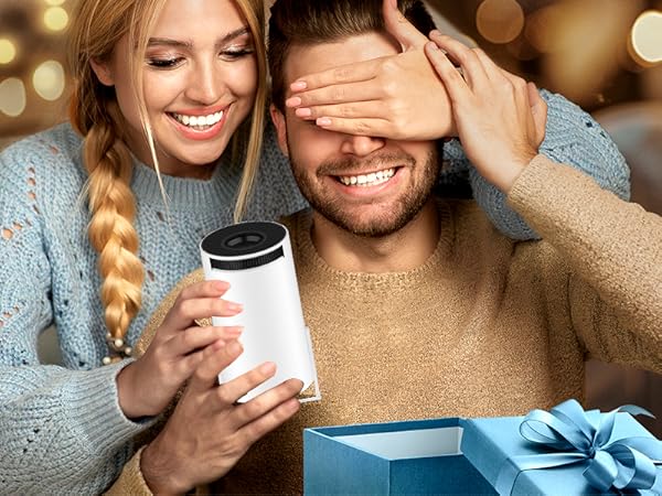 Two people sitting together, one holding a white cup. Blurred background with warm lighting and a gift box visible.