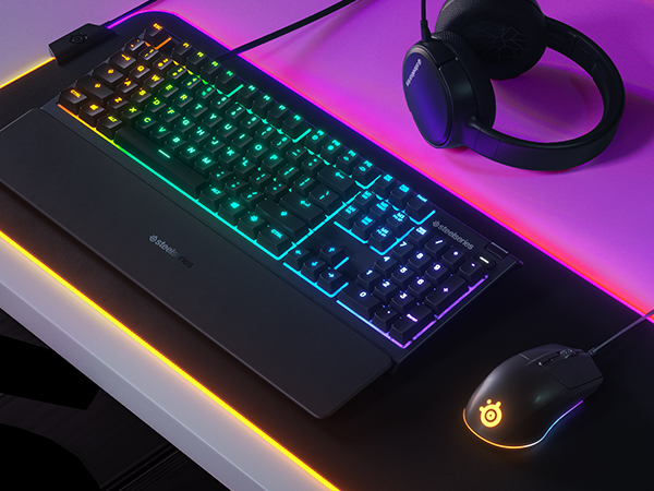 - A SteelSeries desk setup including Apex keyboard, Arctis headset, and Rival 3 mouse