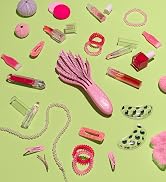 pink curl detangler on green background surrounded by makeup and hair accessories