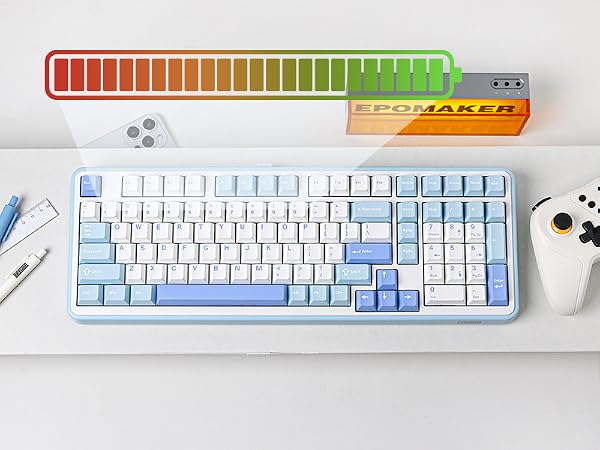 White mechanical keyboard with blue accents on a desk. Above it is a colorful progress bar device and an orange box labeled 'Epomaker'. Gaming controller visible to the side.